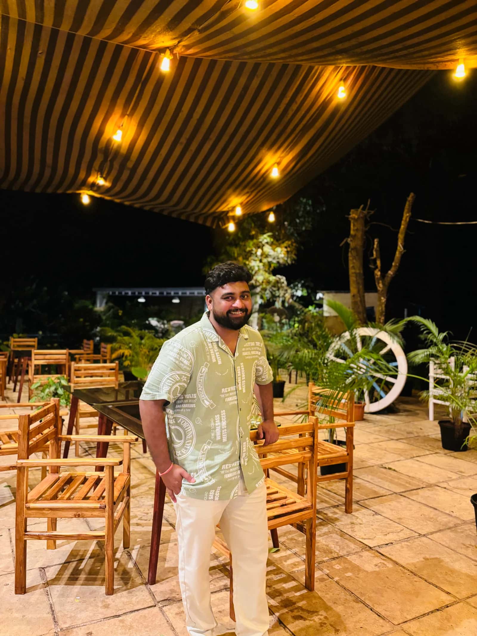 A candid portrait of Pruthviraj beside wooden cafe tables.