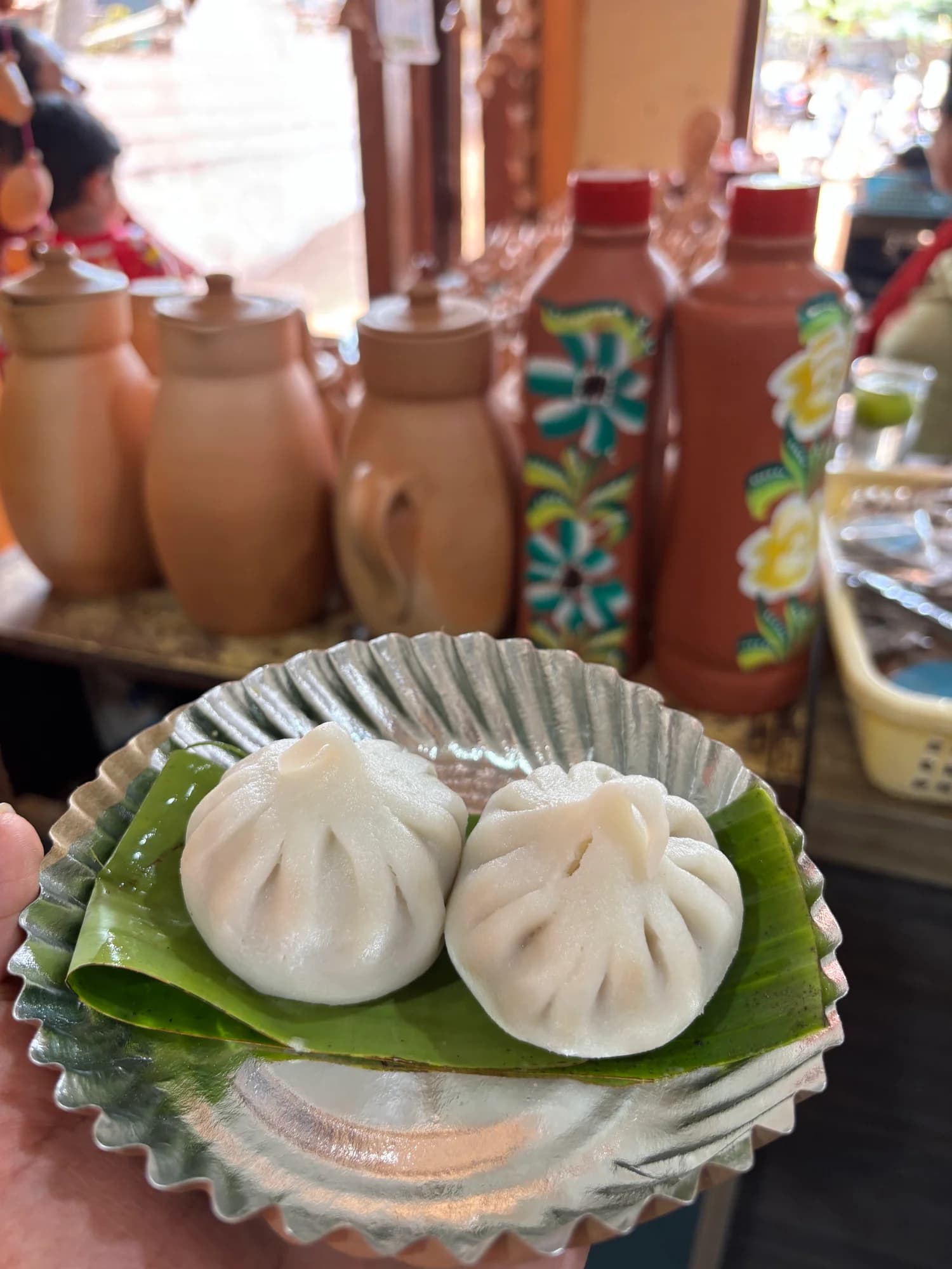 Two steamed dumplings on a leaf-lined foil plate.
