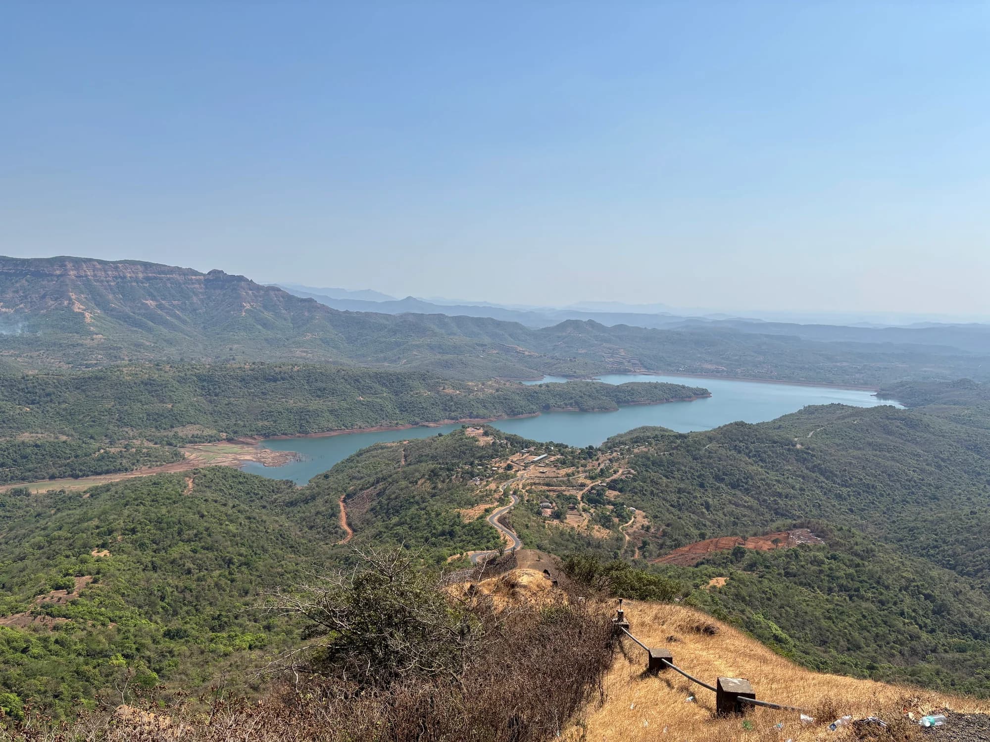 A winding reservoir surrounded by green hills beneath a blue sky.
