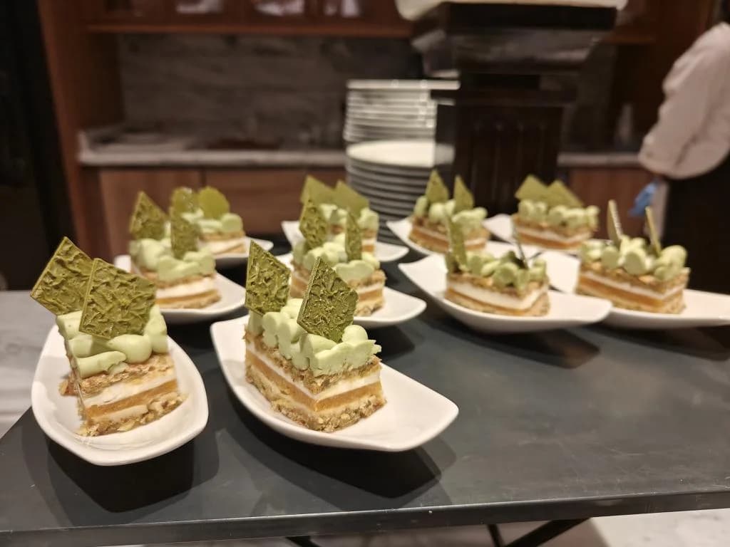 Small layered desserts arranged on white plates at a dessert counter.