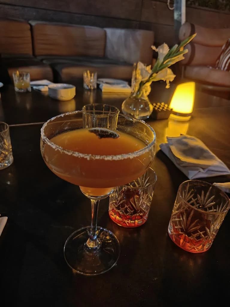 An orange drink in a stemmed glass with a decorative garnish.