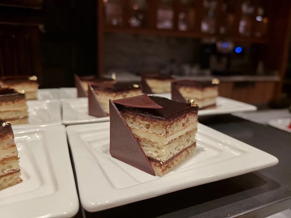 A square slice of layered cake on a white plate.