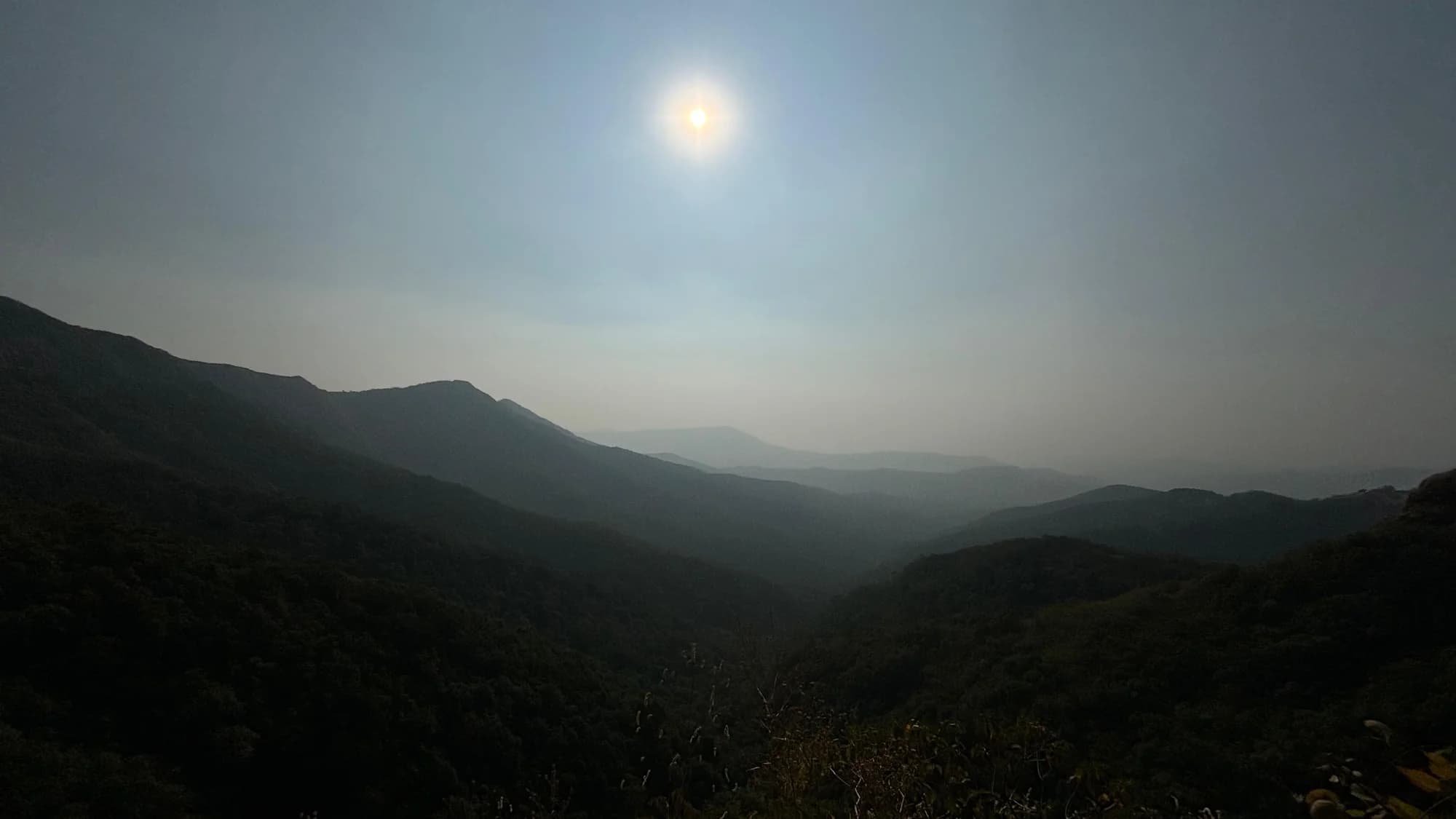 Sunlight falling across layers of hazy green hills.